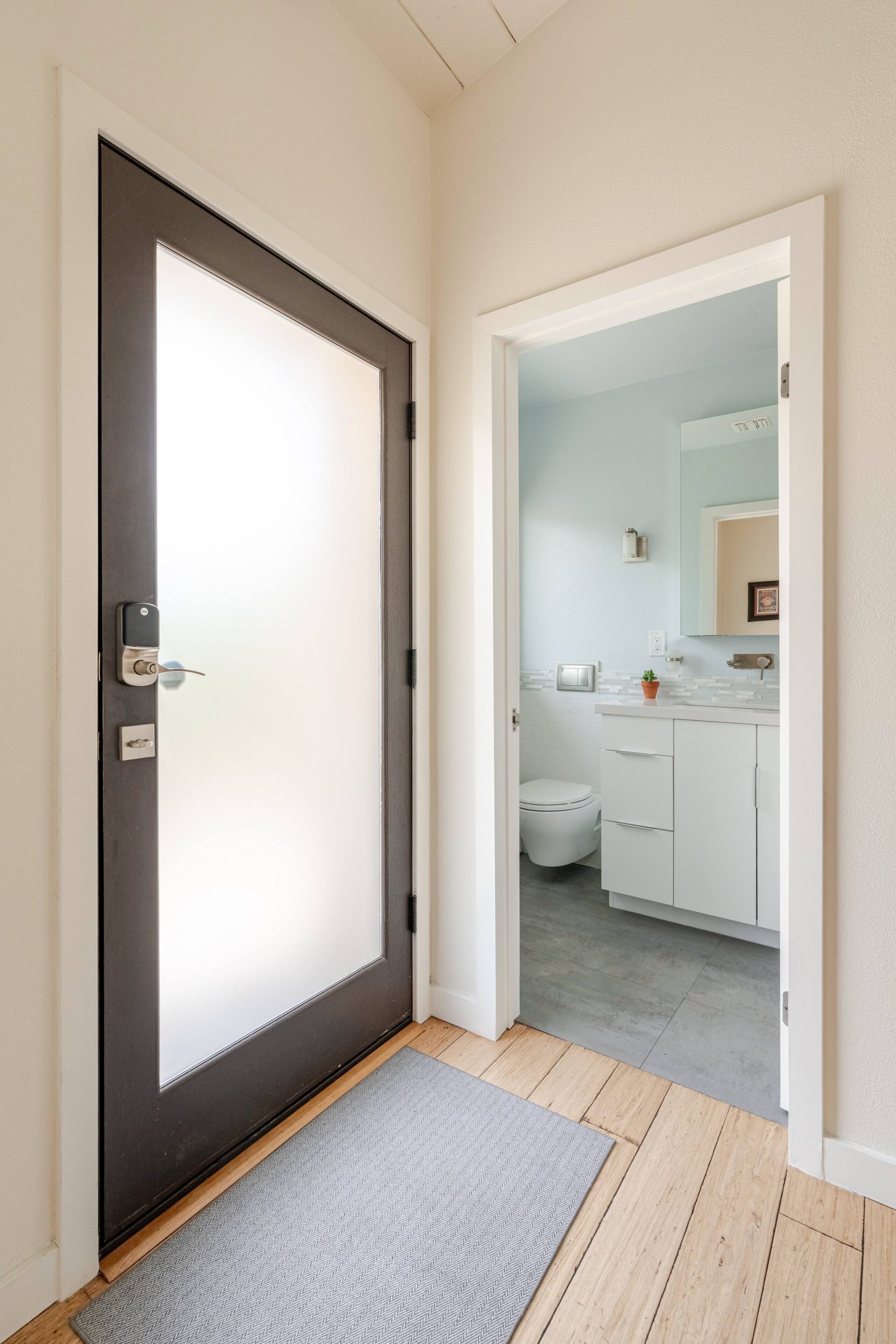 Bathroom with white floating vanity, mosaic tile backsplash and pale blue walls