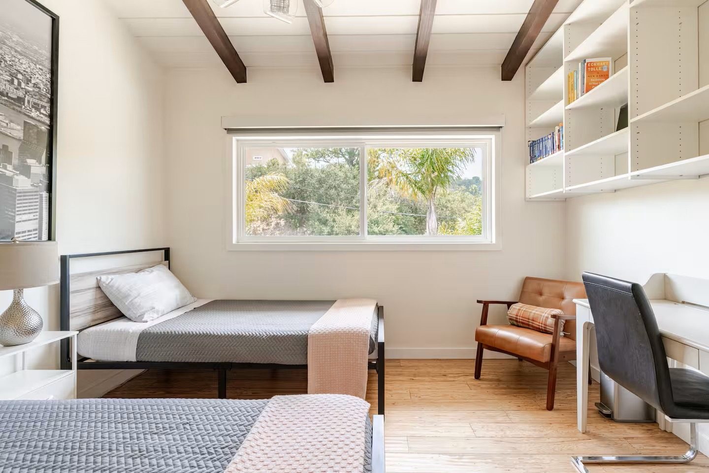 Bedroom desk and reading chair beneath a window with hillside palm view