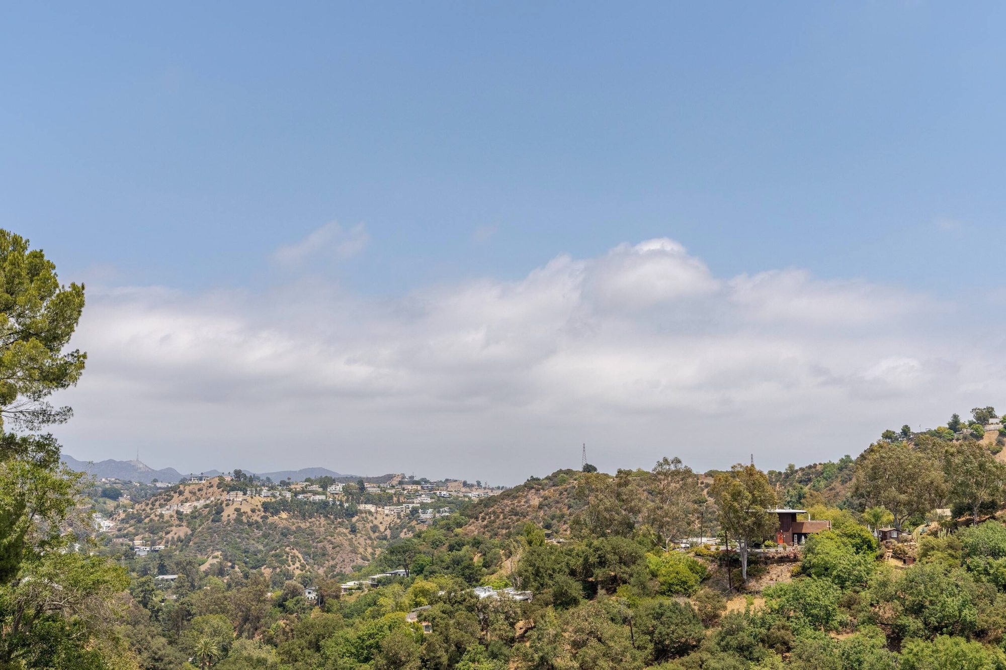 Wide canyon view from the property, with hillside homes and the Hollywood Sign visible in the distance
