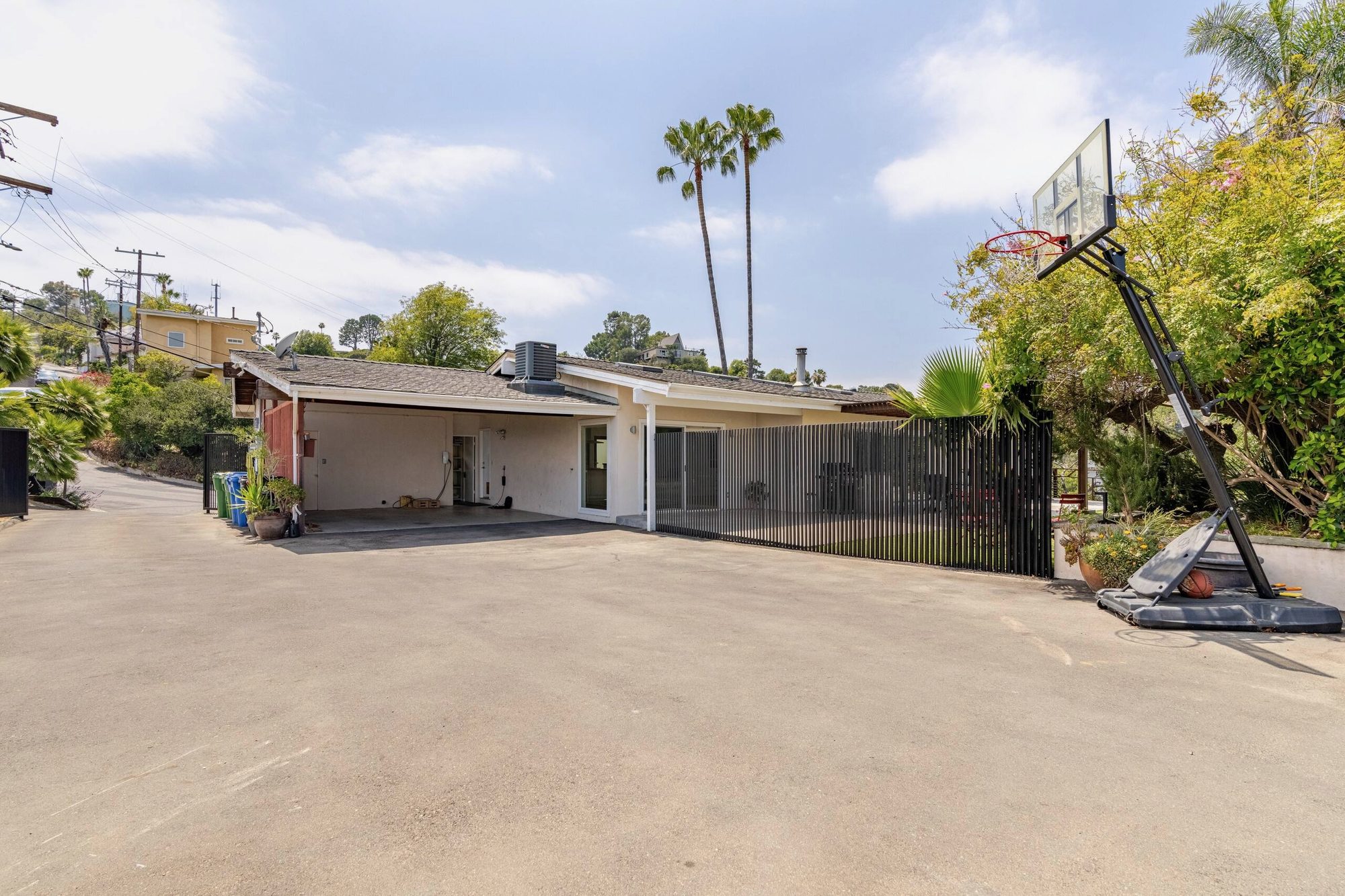 Long driveway with basketball hoop and palm trees