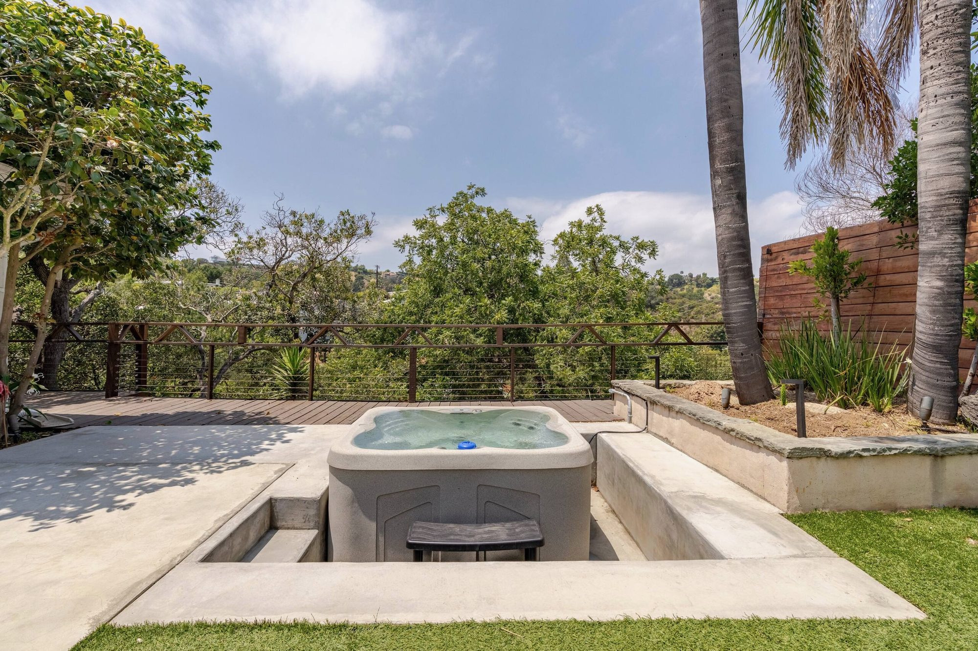 Sunken hot tub on the back patio with a wood deck and hillside trees beyond