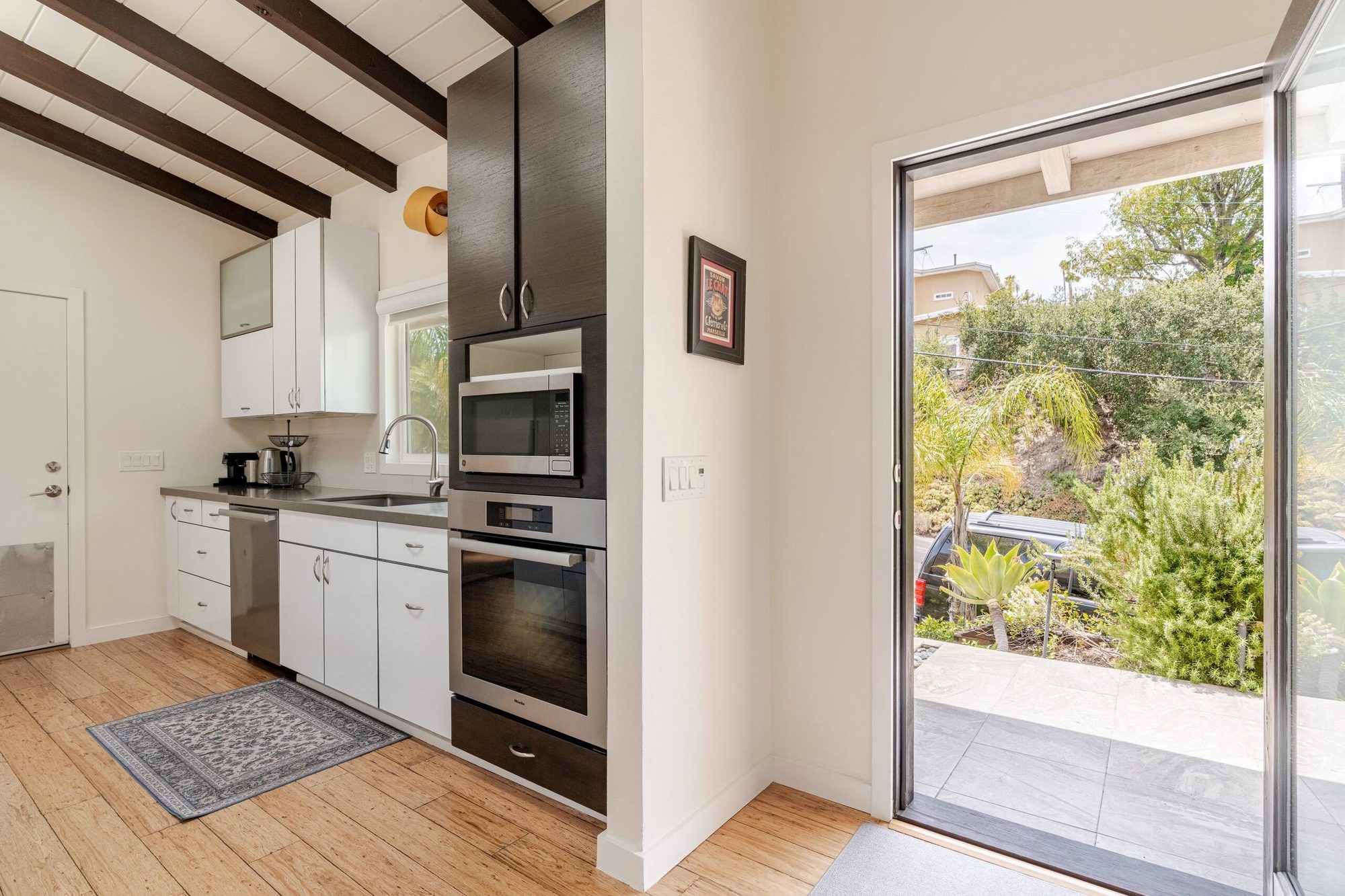 Stacked wall oven and microwave beside a glass door leading out to the side patio
