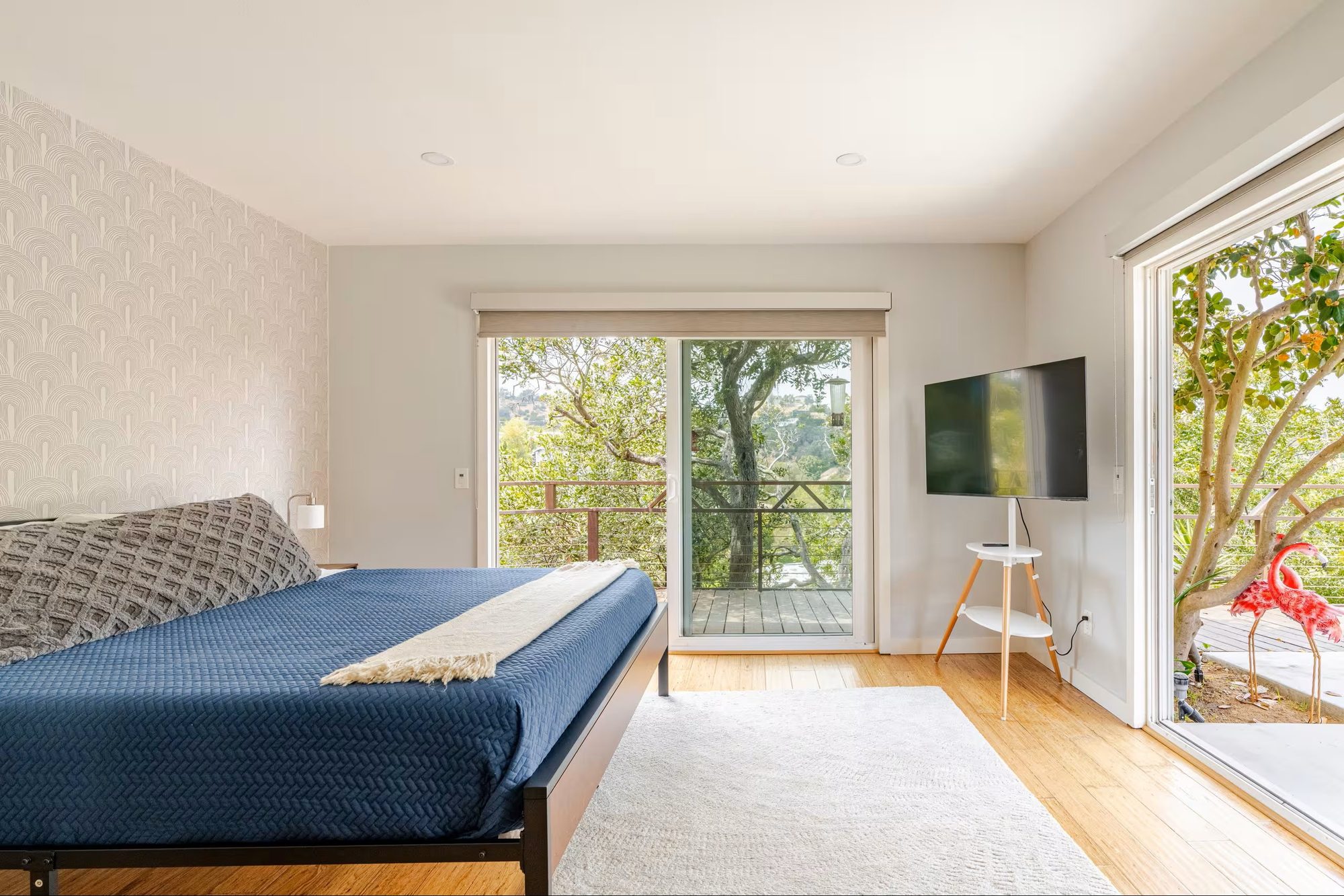 Primary bedroom sliding door open to a deck with garden ornaments and trees