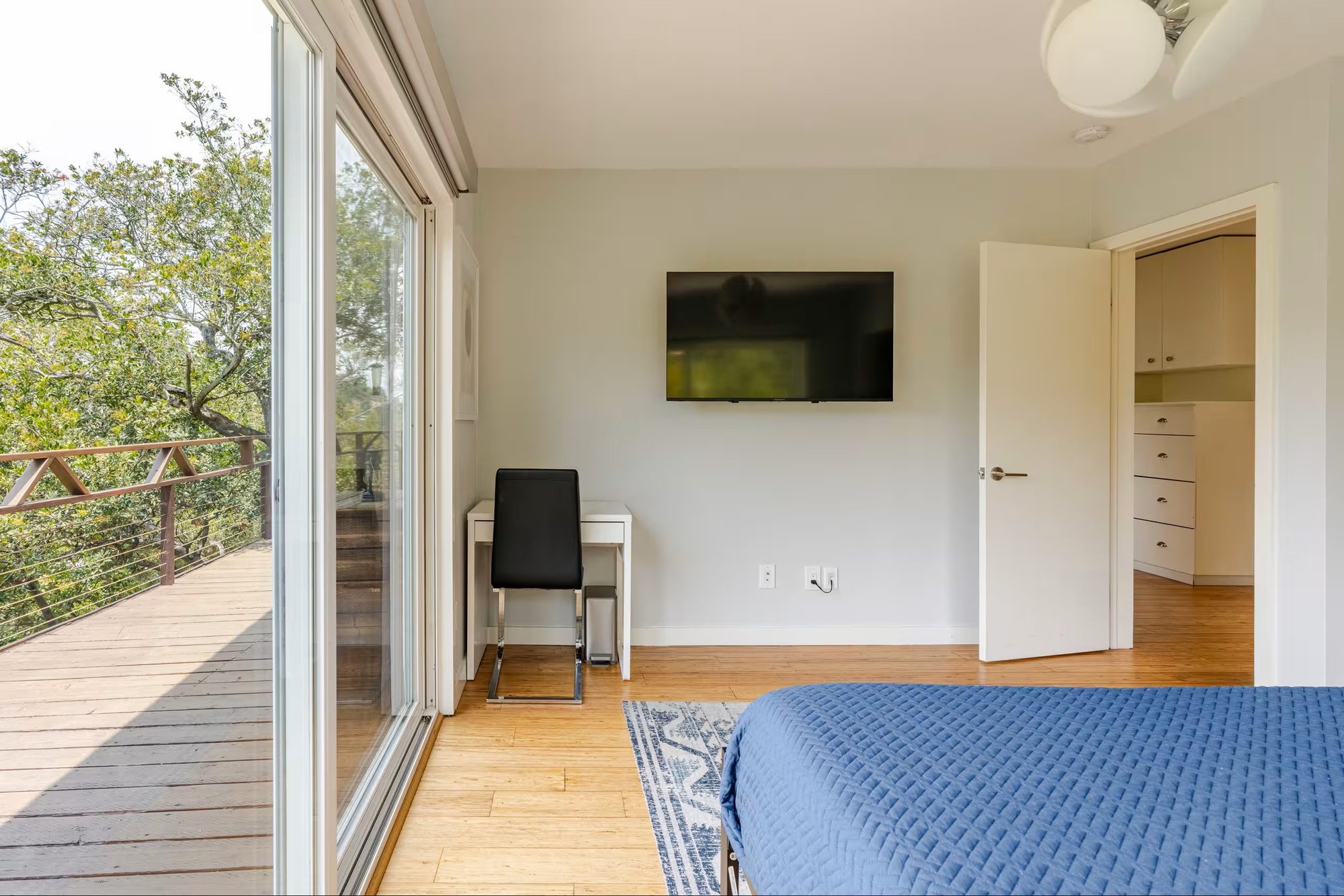 Second bedroom desk and wall-mounted TV beside the door to the private deck